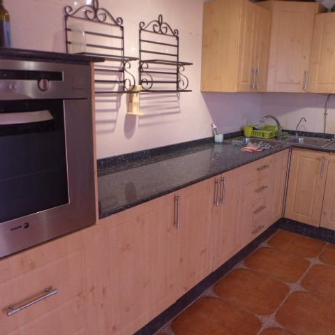 Kitchen with wooden cabinets, black granite worktop, and stainless steel oven in Chirivel, Almeria.