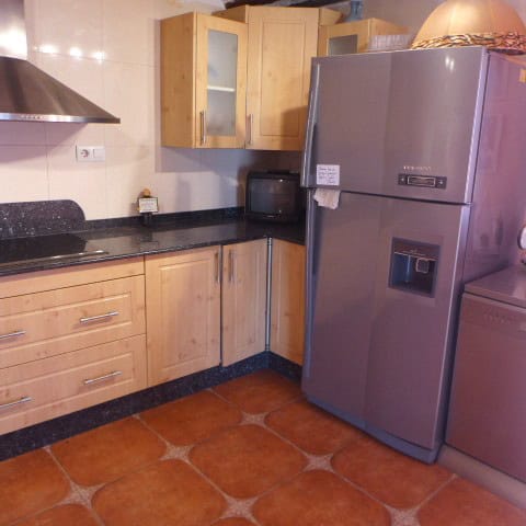 Kitchen with wooden cabinets, refrigerator, microwave, and washing machine in rural Almeria property.