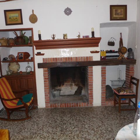 Cozy interior of a village home featuring a traditional brick fireplace and rustic decor.
