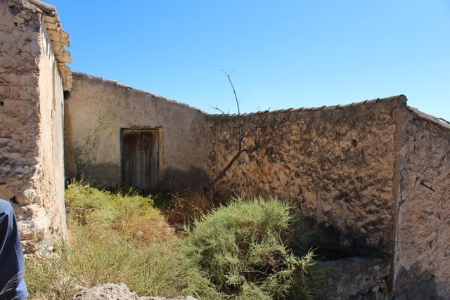 Rural property in Lucar, Almeria, featuring an old stone wall and rustic wooden door, surrounded by.