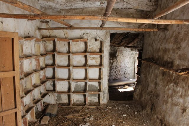 Rural property interior with stone walls and rustic storage shelves in Lucar, Almeria.