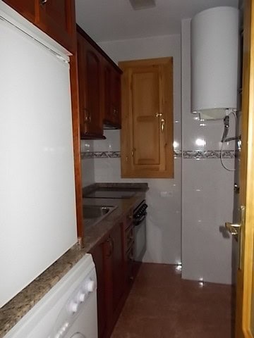 Compact kitchen with wooden cabinets and modern appliances in Tijola, Almeria.