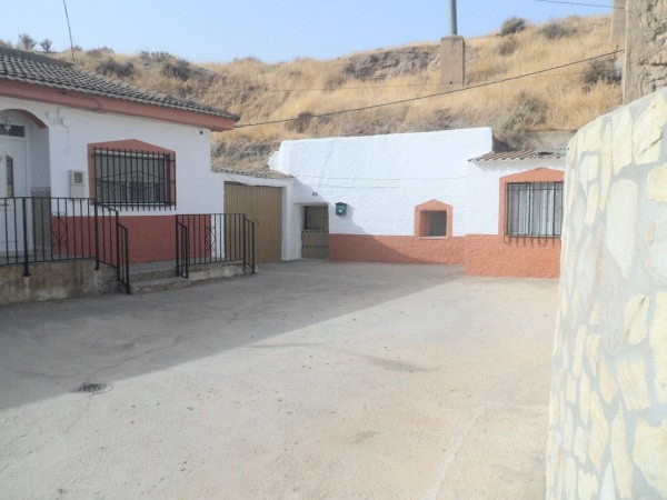 Cave house in Benamaurel, Granada with traditional whitewashed walls and surrounding rural landscape.