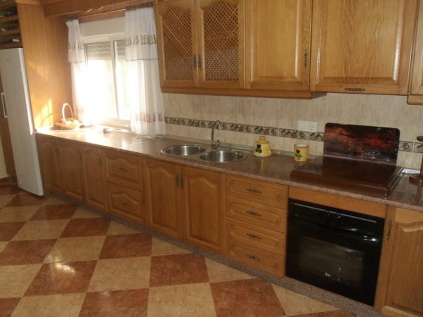Charming cave house interior in Benamaurel, Granada, featuring wooden cabinets and a cozy kitchen se.