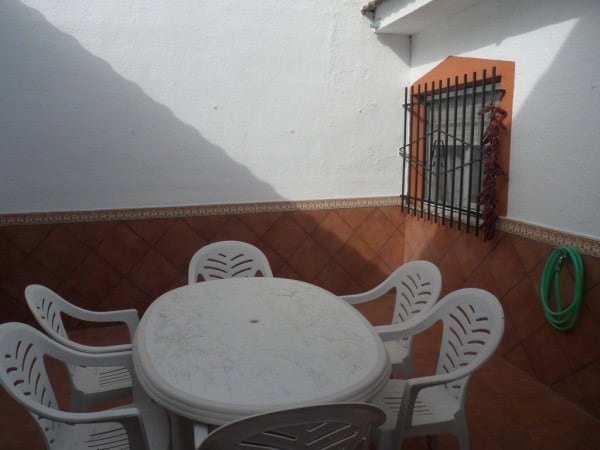 Charming outdoor patio of a cave house in Benamaurel, Granada, featuring a white round table and pla.
