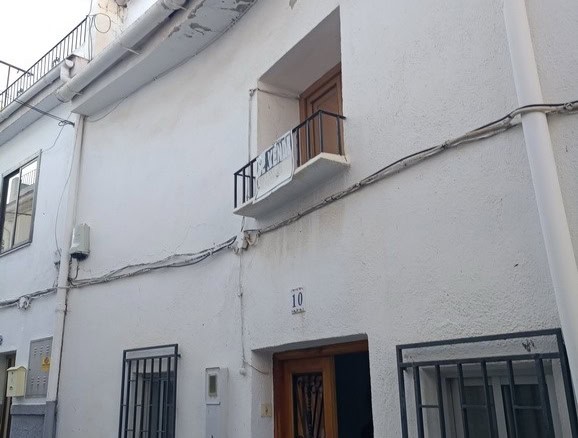 Charming town house in Baza, Granada, featuring a white facade, small balcony, and traditional woode.