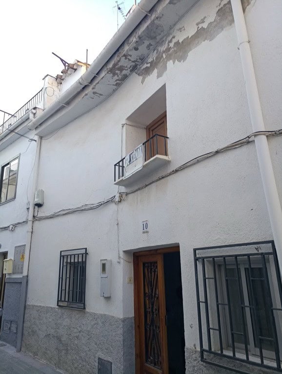 Charming town house in Baza, Granada, featuring a white facade, small balcony, and traditional woode.