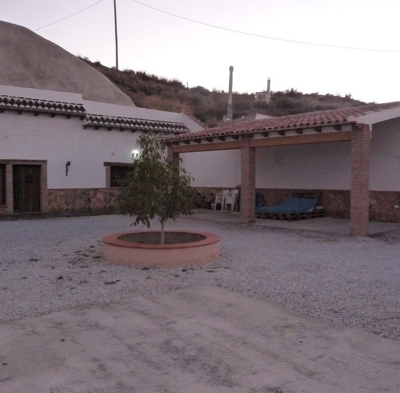 Cave house in Benamaurel, Granada with outdoor courtyard and mountain backdrop.