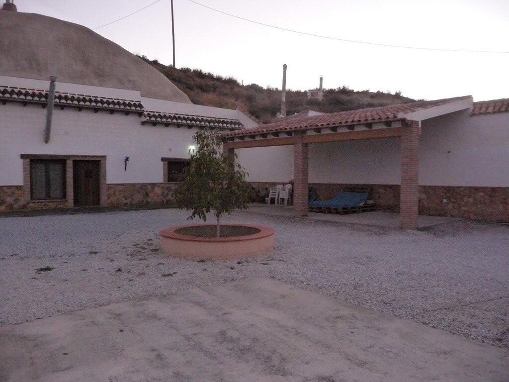 Cave house in Benamaurel, Granada with outdoor courtyard and mountain backdrop.