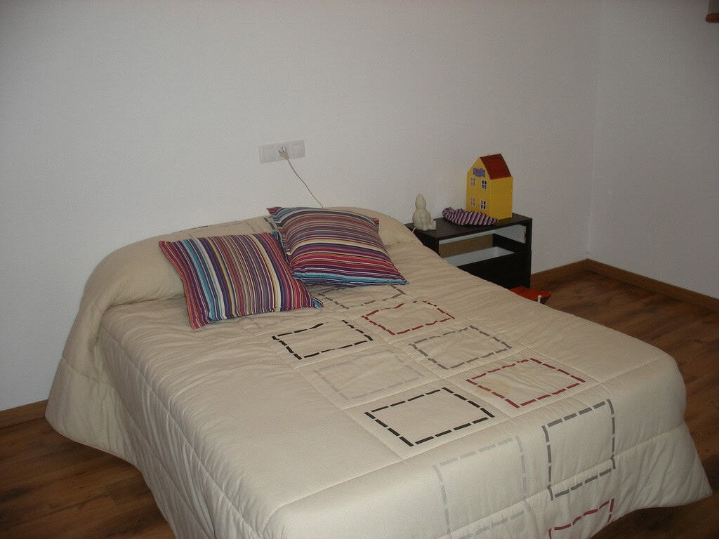 Cave house bedroom with simple decor and colorful pillows, located in Benamaurel, Granada.