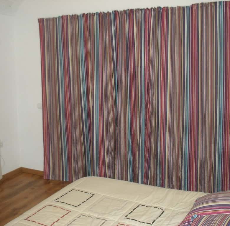 Interior view of a bedroom with striped curtains and a simple bed setup.