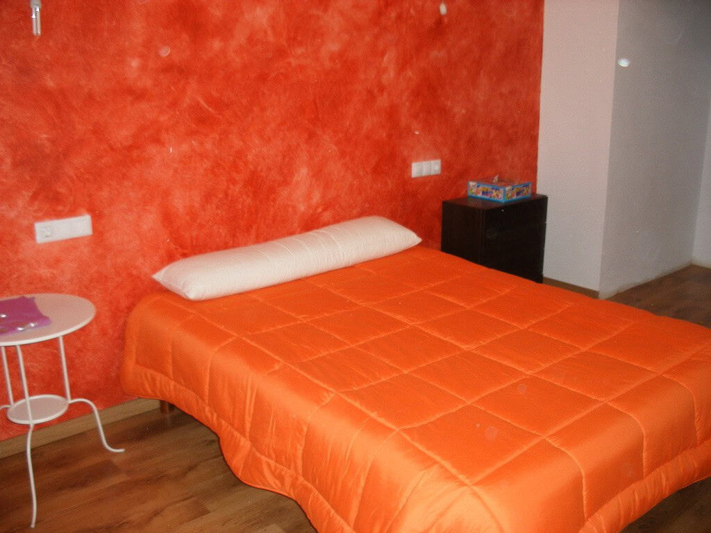 Beautiful bedroom in a cave house with orange walls and modern furnishings in Benamaurel, Granada.