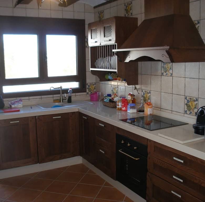 Cave house kitchen in Benamaurel, Granada with wooden cabinets and modern appliances.