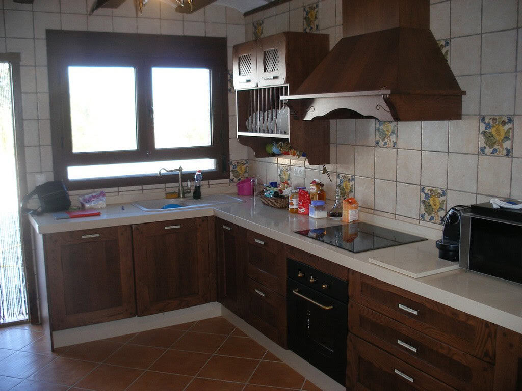 Cave house kitchen in Benamaurel, Granada with wooden cabinets and modern appliances.
