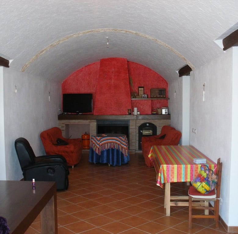 Cave house interior with cozy living area, fireplace, and colorful furniture in Benamaurel, Granada.