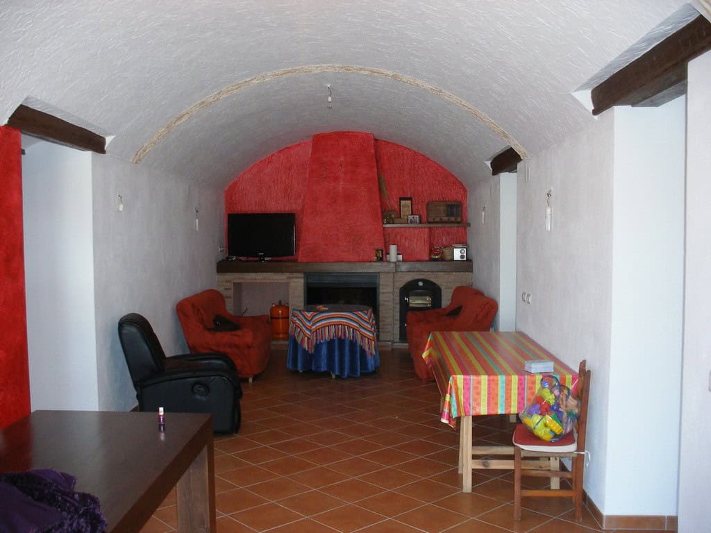 Cave house interior with cozy living area, fireplace, and colorful furniture in Benamaurel, Granada.