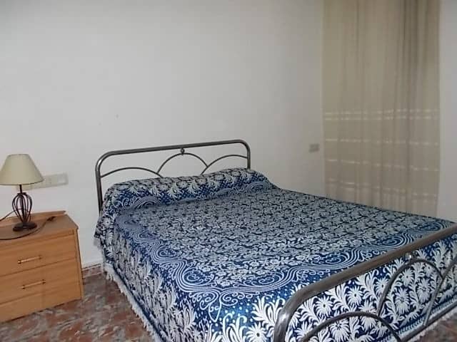 Cozy bedroom with metal bed frame and blue patterned bedding in Tijola, Almeria.