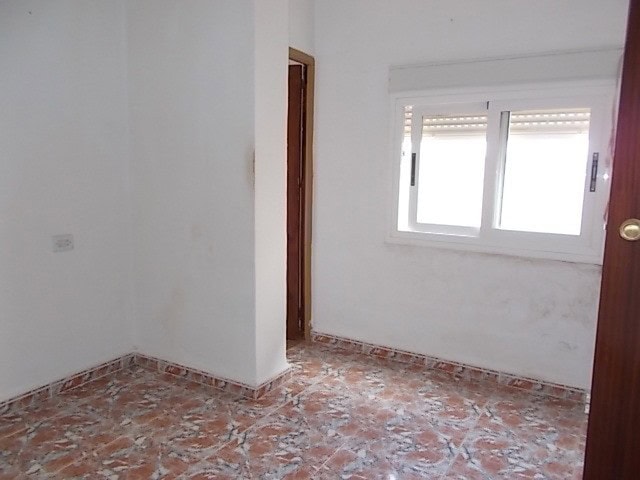 Interior view of a town house in Tijola, Almeria, showing a simple room with a window and tiled floo.