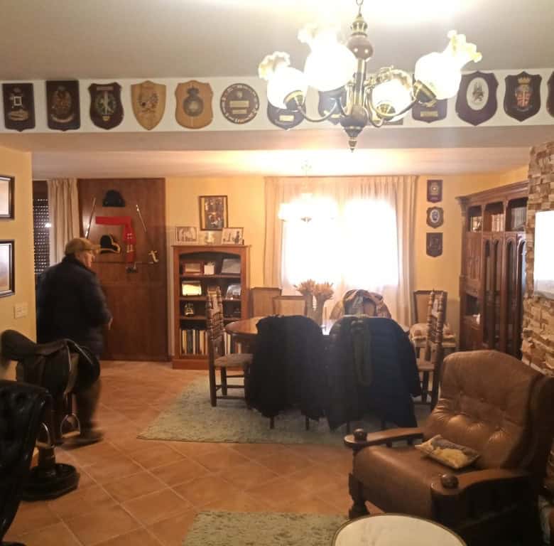 Spacious living room with wooden furniture, decorative shields, and a warm ambiance in Oria, Almeria.