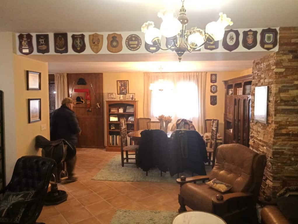 Spacious living room with wooden furniture, decorative shields, and a warm ambiance in Oria, Almeria.