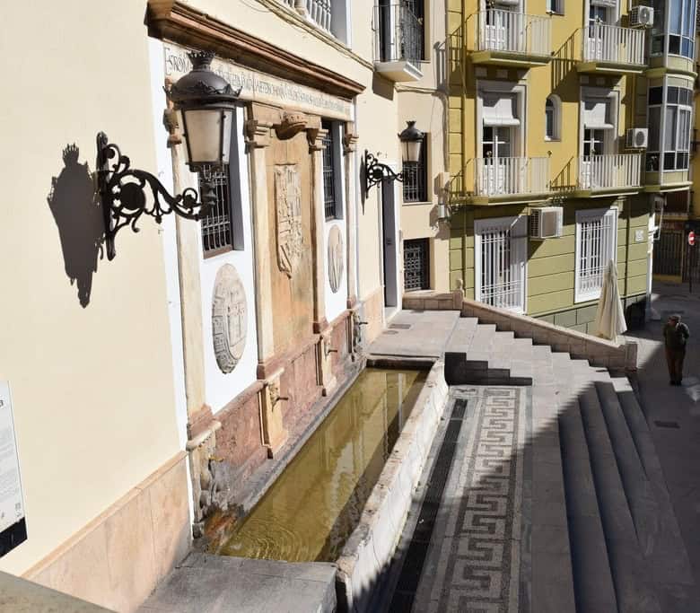 Commercial building in Baza, Granada with historic architecture and outdoor fountain.