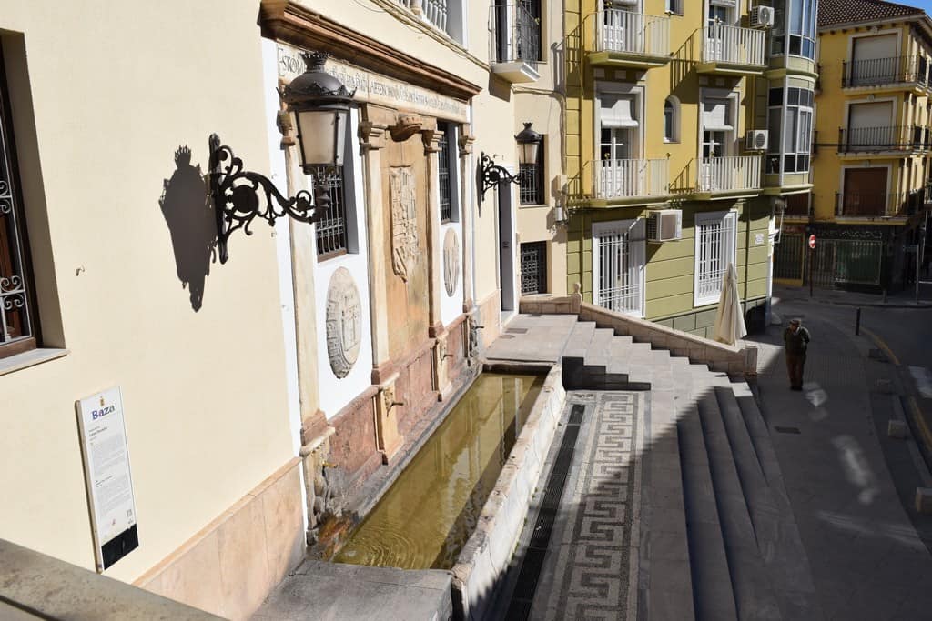 Commercial building in Baza, Granada with historic architecture and outdoor fountain.