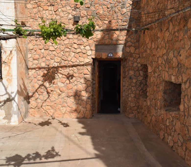 Cave house entrance in Baza, Granada with rustic stone walls and shaded courtyard.