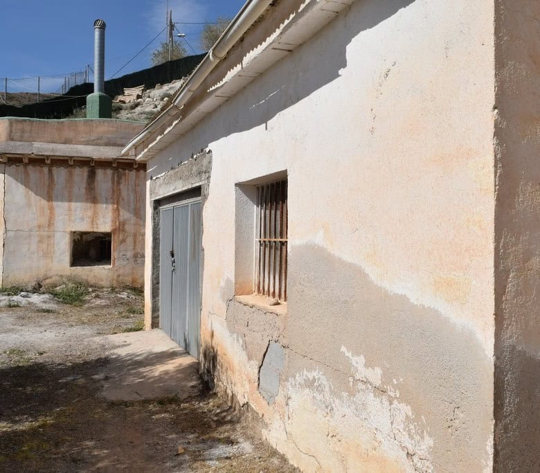 Cave house exterior in Baza, Granada with rustic walls and small barred window.