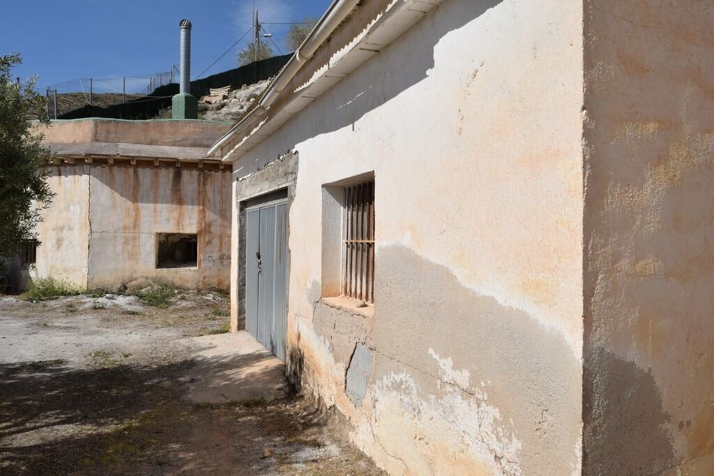 Cave house exterior in Baza, Granada with rustic walls and small barred window.