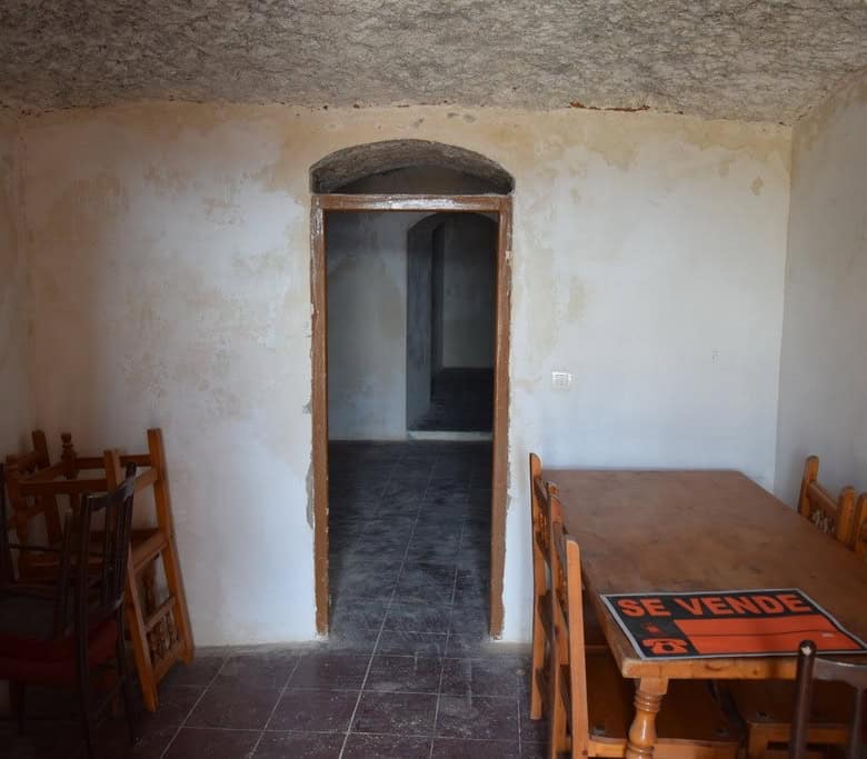 Interior view of a cave house in Baza, Granada with rustic walls and wooden furniture.