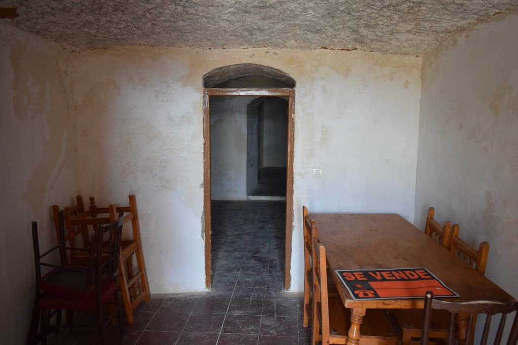 Interior view of a cave house in Baza, Granada with rustic walls and wooden furniture.