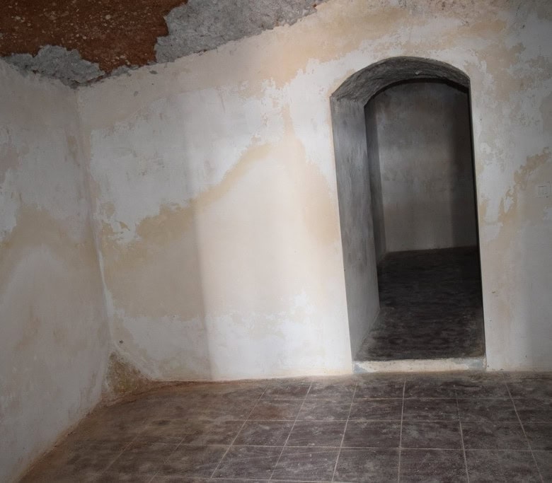 Cave house interior with arched doorway and rustic walls in Baza, Granada, offering unique living sp.