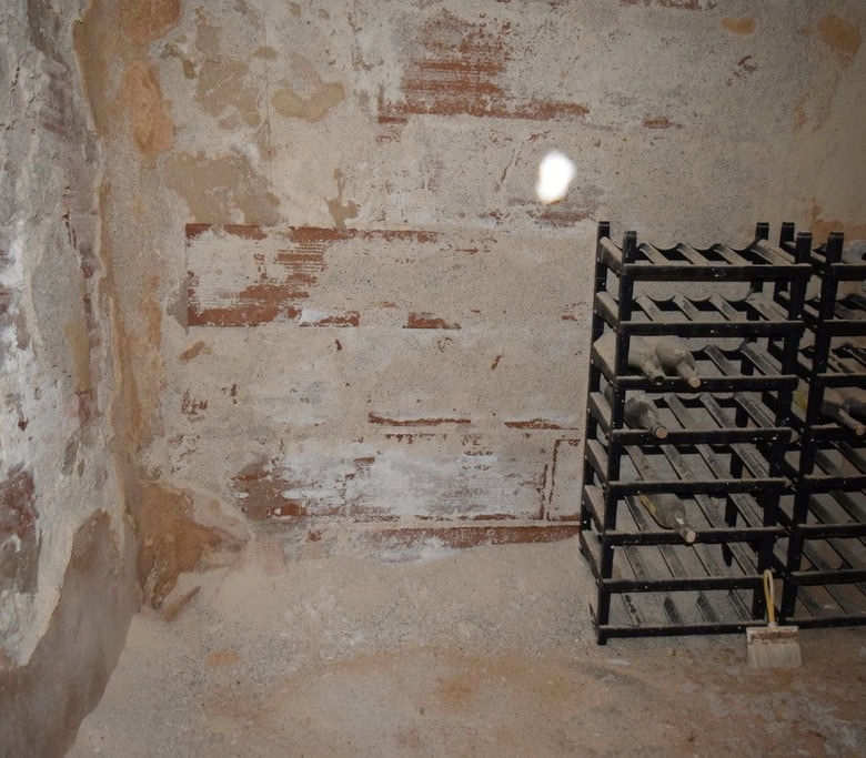 Interior view of a rustic cave house in Baza, Granada, showing exposed brick walls and storage racks.