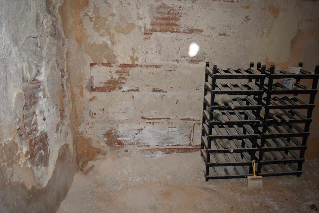 Interior view of a rustic cave house in Baza, Granada, showing exposed brick walls and storage racks.