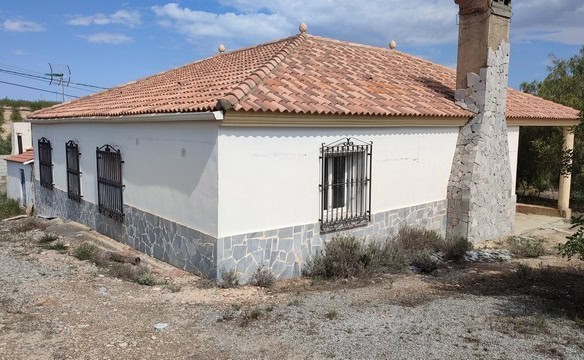 Rural property in Somontin, Almeria, featuring a white exterior, tiled roof, and stone foundation, i.