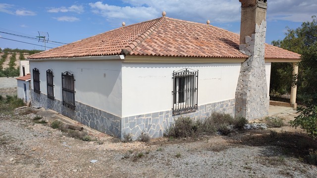 Rural property in Somontin, Almeria, featuring a white exterior, tiled roof, and stone foundation, i.