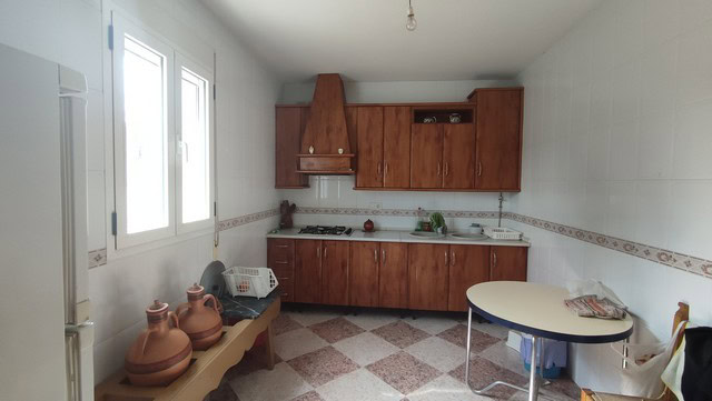 Traditional rural kitchen in Somontin, Almeria, with wooden cabinets, tiled floor, and basic applian.