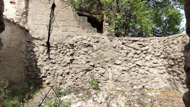 Ancient stone wall of a rural property in Tijola, Almeria, surrounded by greenery and natural landsc.