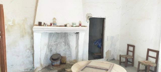 Traditional rural house interior in Benamaurel, Granada, with rustic walls and simple furnishings.
