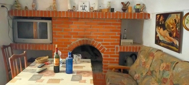 Interior of a cave house in Cortes de Baza, Granada with brick fireplace and rustic decor.