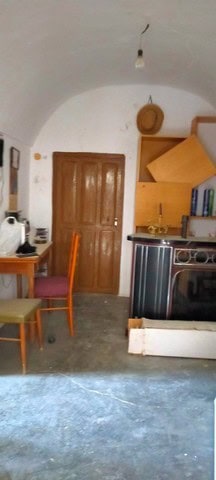 Charming cave house interior with wooden door, kitchen area, and cozy furnishings in Cortes de Baza,.