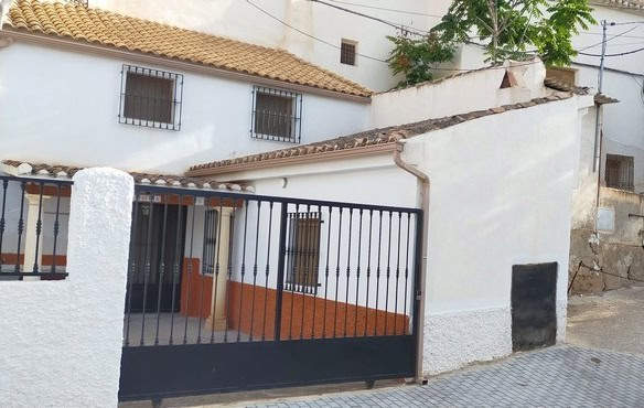 Traditional cave house with white walls and gated entrance in Benamaurel, Granada.