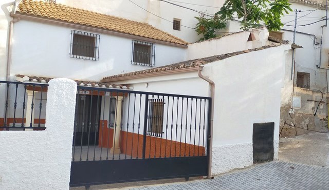 Traditional cave house with white walls and gated entrance in Benamaurel, Granada.