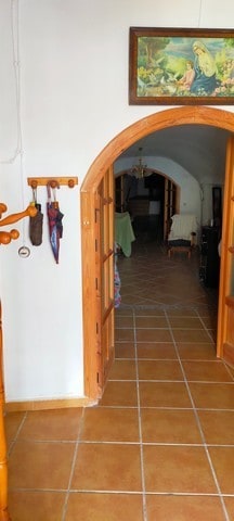Charming cave house entrance in Benamaurel, Granada, with wooden door frame and terracotta tiled flo.