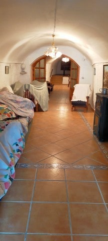 Cave house interior in Benamaurel, Granada with arched ceiling and rustic decor.