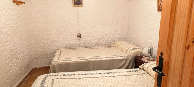 Interior of a traditional cave house in Benamaurel, Granada, showcasing rustic bedrooms.