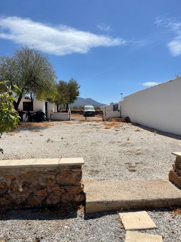 Outdoor view of village property in Gor, Granada, featuring a gravel yard, white walls, and scenic m.