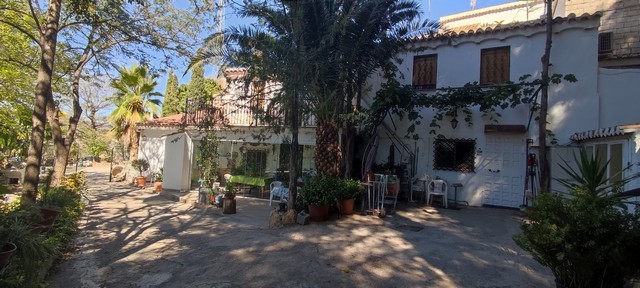 Cave house in Caniles, Granada, with outdoor seating and lush greenery.