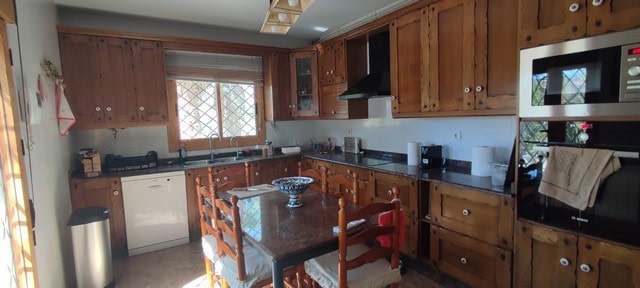 Bright kitchen with wooden cabinets and modern appliances in Caniles, Granada.