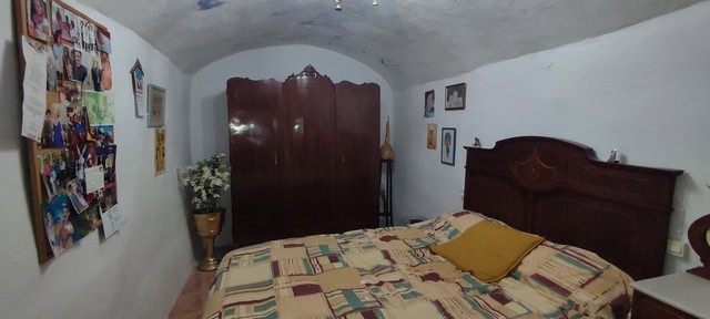 Cozy cave house bedroom in Caniles, Granada with traditional decor and rustic charm.